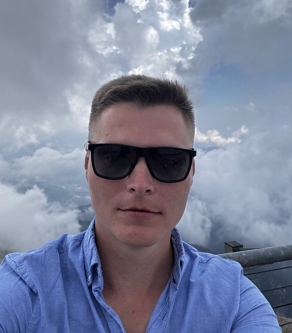 Selfie of Alexander Valenchits in sunglasses above the clouds